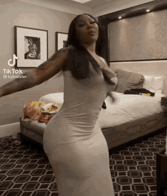a woman in a white dress is dancing in a bedroom with a bed .