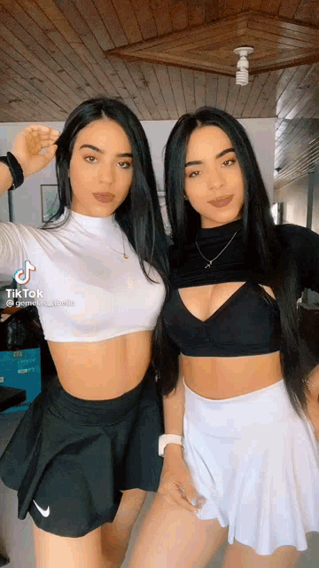 two women are standing next to each other wearing skirts and crop tops with tiktok written on the bottom