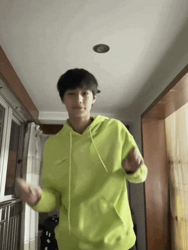 a person in a neon green hoodie is dancing in a hallway