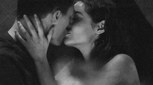 a man and a woman are kissing each other in a black and white photo .