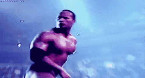 a man without a shirt is standing in front of a crowd in a dark room .