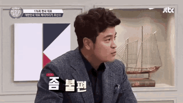 a man in a suit is sitting in front of a sign that says jtbc on it
