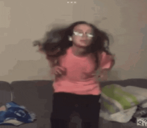 a little girl is dancing on a couch with headphones on .