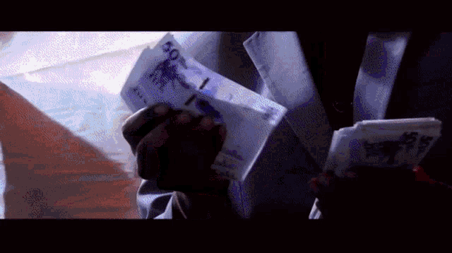 a person is holding a bunch of money in their hands and one of the bills has the number 100 on it
