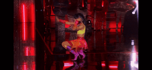 a woman in a yellow top and red skirt is dancing on a stage