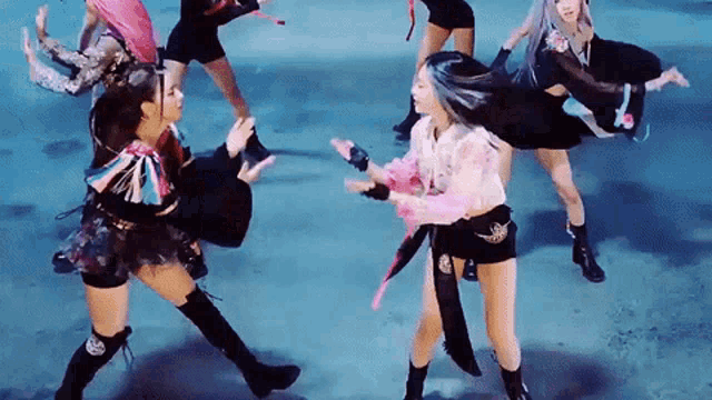 a group of women are dancing on a stage and one of them is wearing a pink shirt .