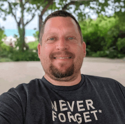 a man with a beard wears a shirt that says never forget
