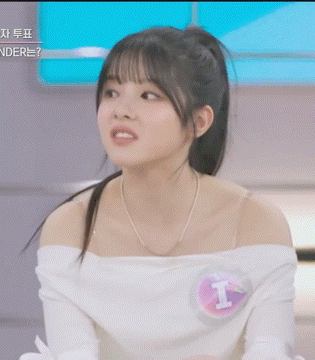 a woman wearing a white off the shoulder top with the letter i on it