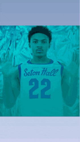 a man wearing a seton hall 22 jersey holds up his hands