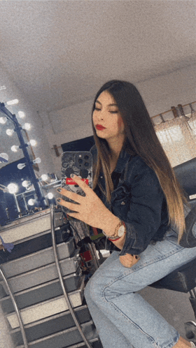 a woman sitting in front of a mirror taking a selfie with her phone