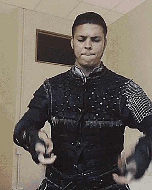 a man in a black leather jacket with chain mail on his arms