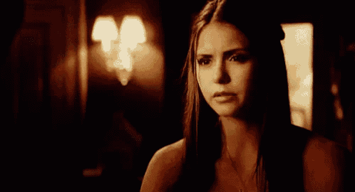 a woman in a dark room with a necklace on her neck