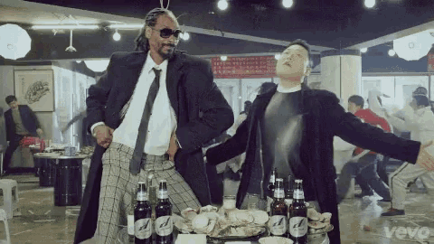 snoop dogg and psy are dancing in a room with bottles of beer .