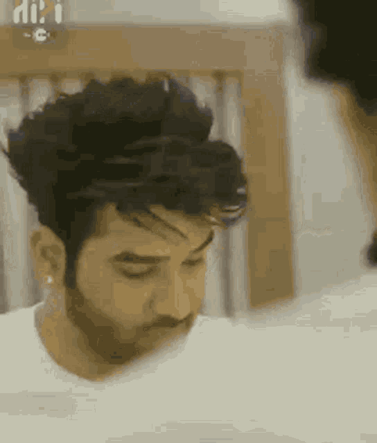 a man with a beard and earrings is sitting on a bed .