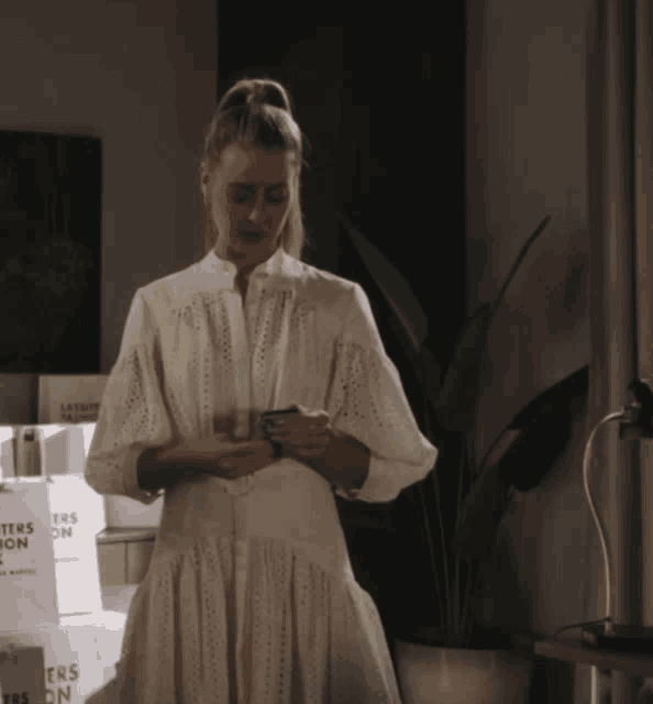 a woman in a white dress stands in front of a stack of white boxes that say letters on them
