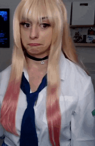 a woman with blonde hair and a blue tie makes a funny face