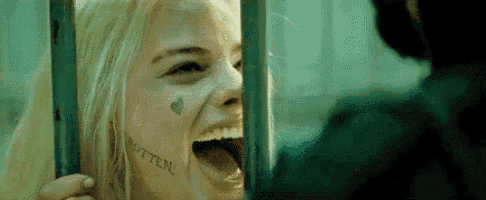 a woman with a tattoo on her face is smiling behind bars .