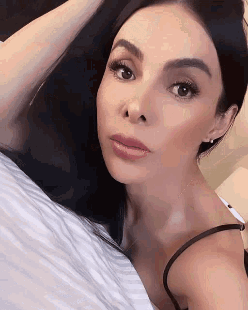 a woman laying on a bed with her hand on her hair