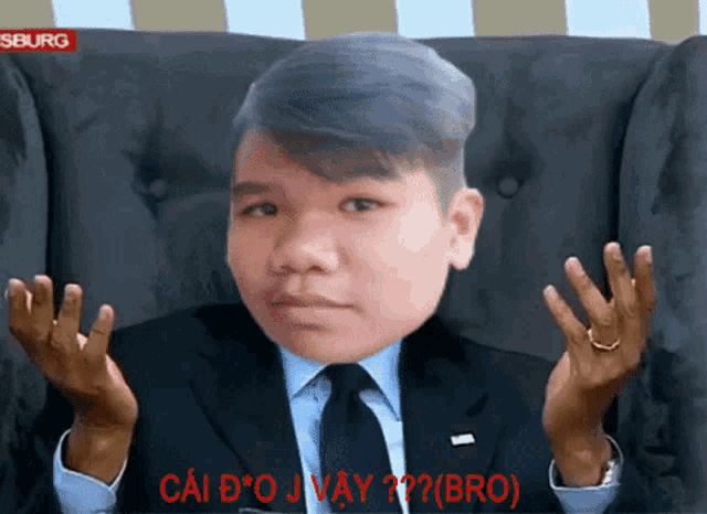 a man in a suit and tie is sitting in a chair with his hands up in front of a red sign that says seburg