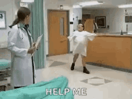 a doctor is standing next to a woman in a hospital gown dancing in a hospital hallway .