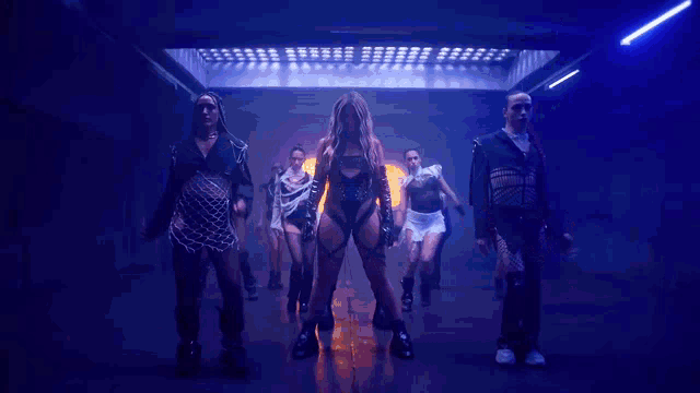 a group of people are dancing in a dark room with a woman in the middle .