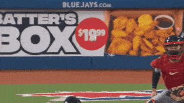 a batter 's box for $ 19.99 is advertised on the wall of a baseball field