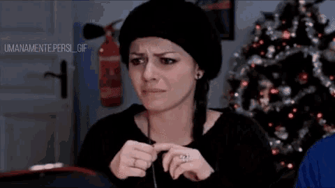 a woman with a ring on her finger is making a funny face in front of a fire extinguisher and a christmas tree