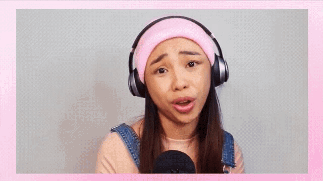 a woman wearing headphones and a pink headband is making a face .