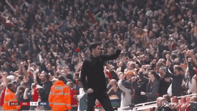 a man stands in front of a crowd with a scoreboard that says abs 1-0 mun