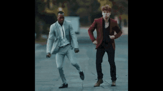 two men in suits and jackets are dancing on the street .