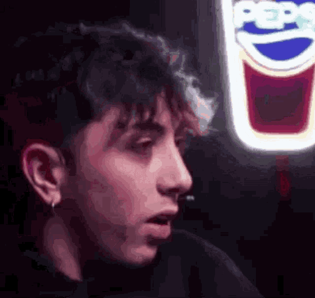 a man is sitting in front of a pepsi sign .