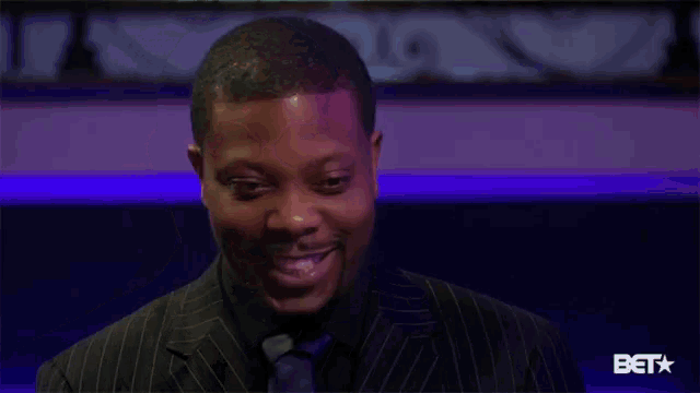 a man in a suit and tie is looking up at something in a dark room .