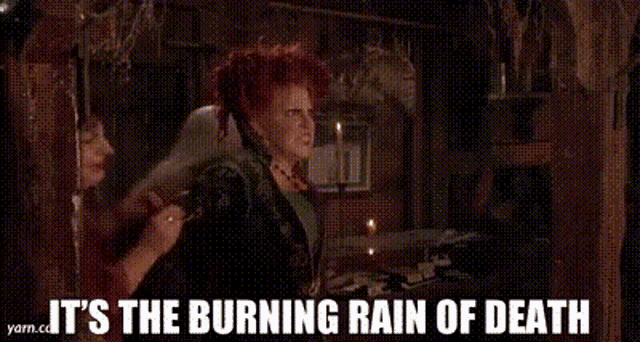 three women are standing next to each other in a dark room with the words `` it 's the burning rain of death '' above them .