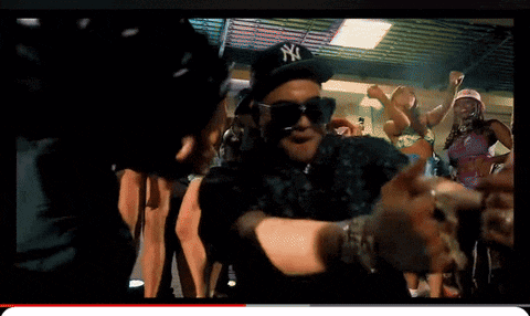 a man wearing a ny hat and sunglasses is dancing in a crowd
