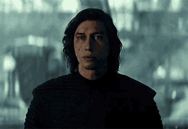 a close up of a man with long hair and a black jacket .