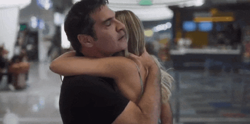 a man is hugging a woman in an airport .