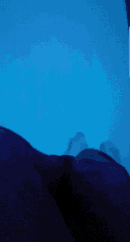 a person laying on a bed in front of a purple light