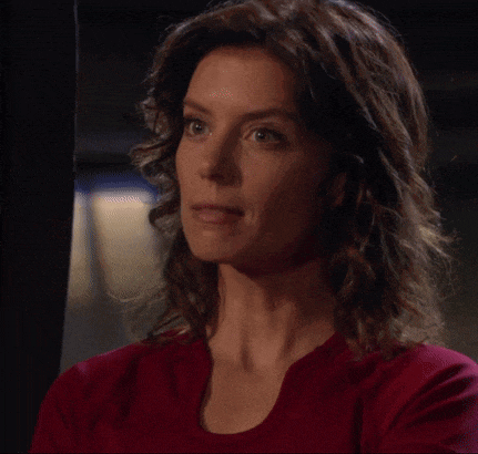 a woman with curly hair is wearing a red sweater