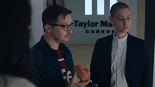 a man and a woman standing in front of a sign that says taylor ma carbon