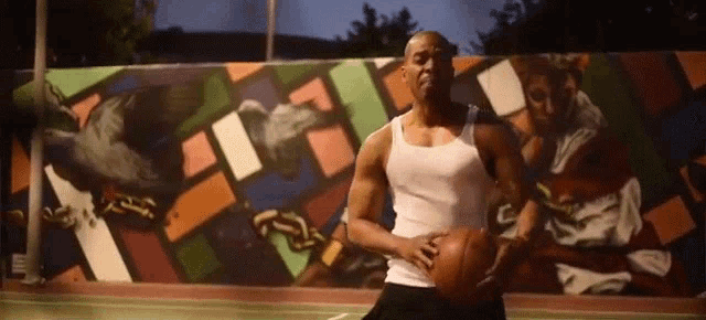 a man in a white tank top is holding a basketball in front of a colorful wall