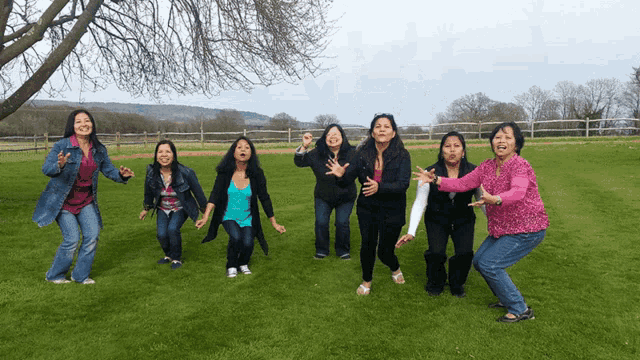 a group of women are standing in a grassy field