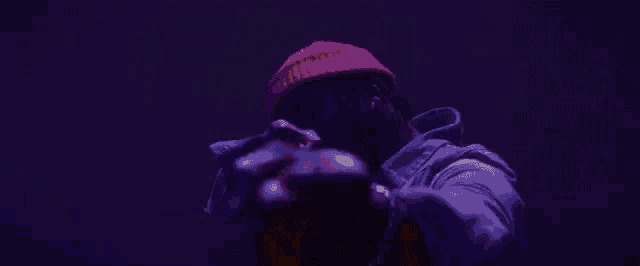 a man in a red hat is giving the middle finger in the dark .