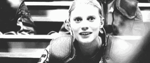 a black and white photo of a woman sitting in a stadium .