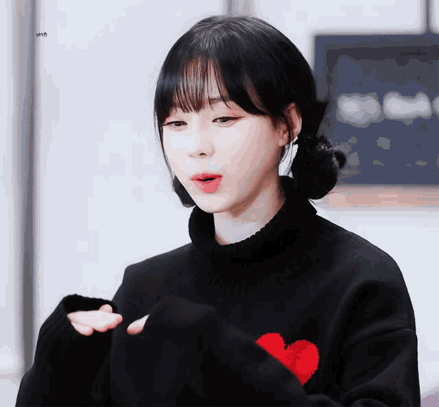 a girl wearing a black sweater with a red heart on the front