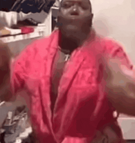 a man wearing a pink robe is dancing in a room .
