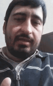 a man with a beard is wearing a black jacket