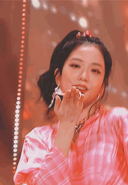 a woman in a pink shirt blowing a kiss