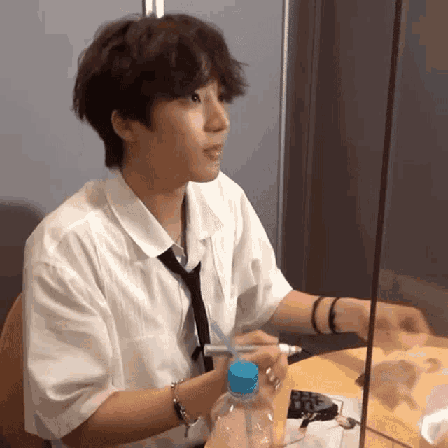 a young man sitting at a table with a bottle of water
