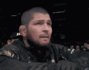 a man with a beard is wearing a black jacket with a gold emblem on it