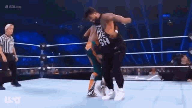 a man is kicking another man in the face while wrestling in a ring .